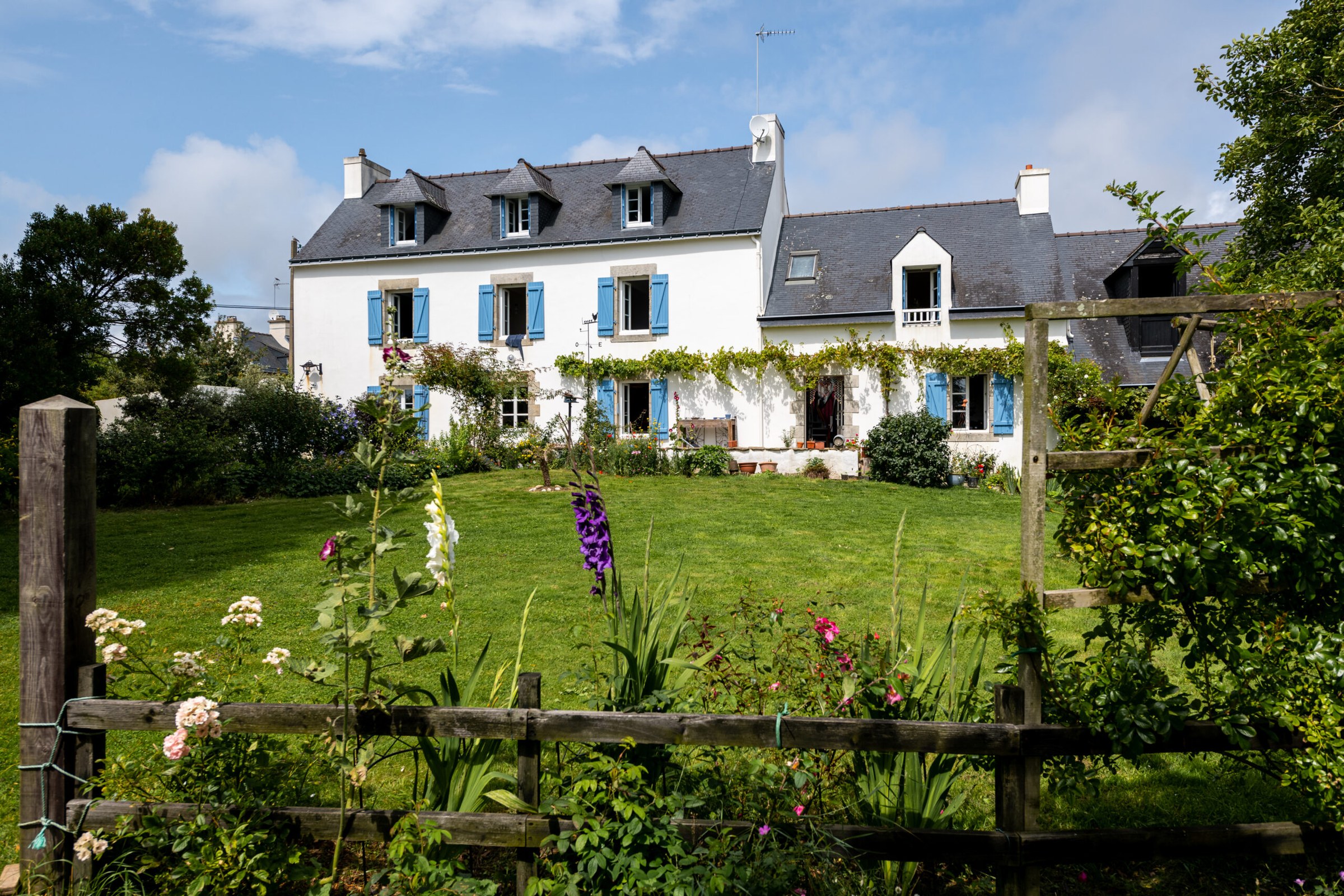 Façade en granit d'une maison typique bretonne avec volets de bois et toiture en ardoise